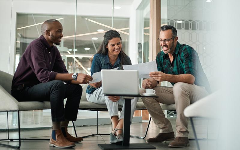 Three people in an office looking at a laptop